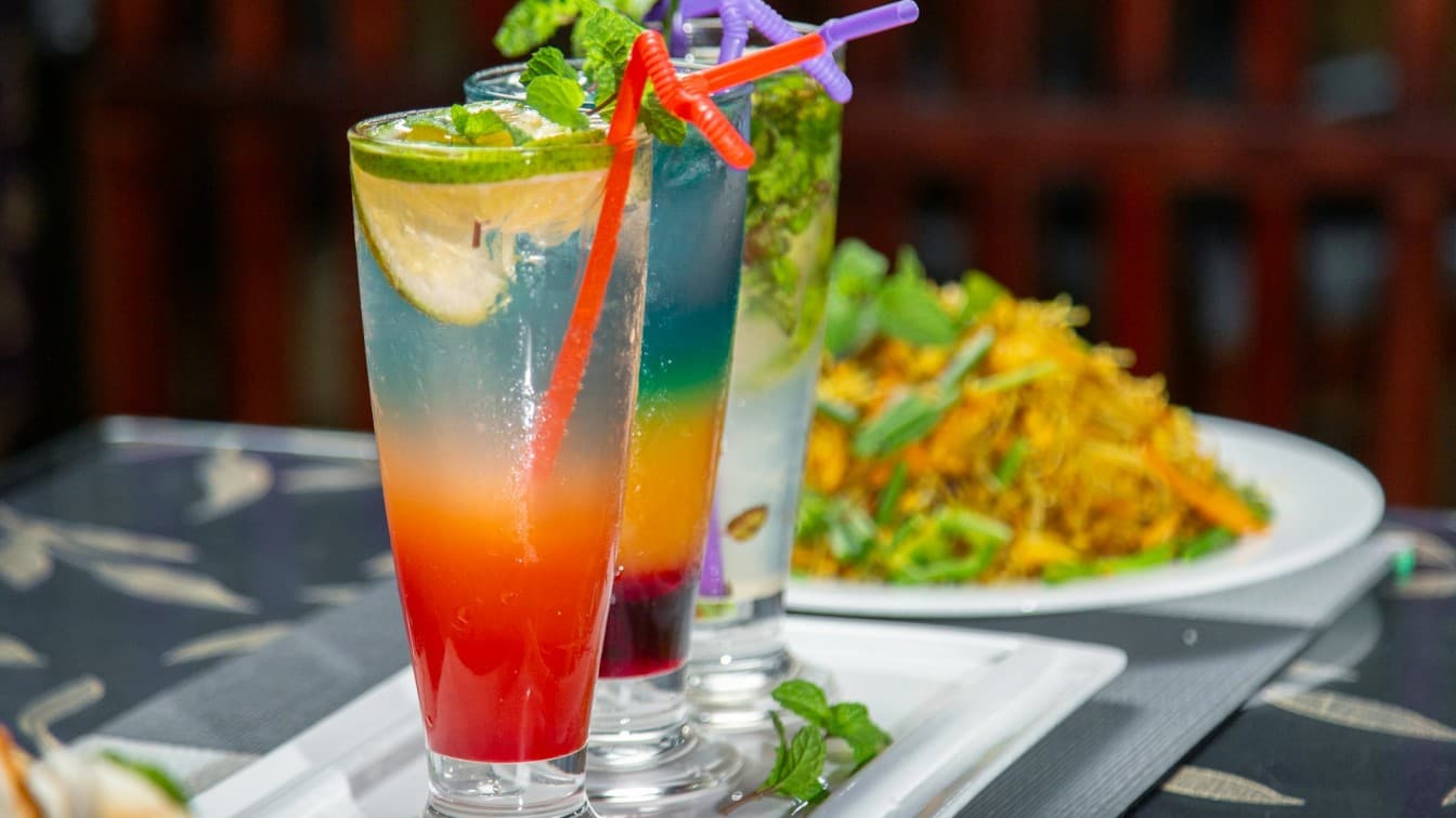 3 glasses of chilled ombre-coloured drinks with colourful straws lined diagonally next to each other